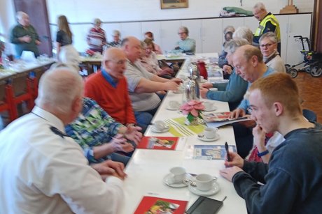 Mehrere Menschen sitzen an langen Tischen.