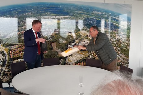 2 Männer stehen an einem runden Tisch.