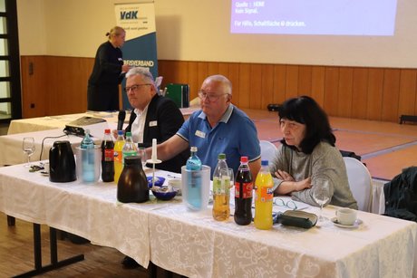Zwei M&auml;nner und eine Frau sitzen an einem Tisch.