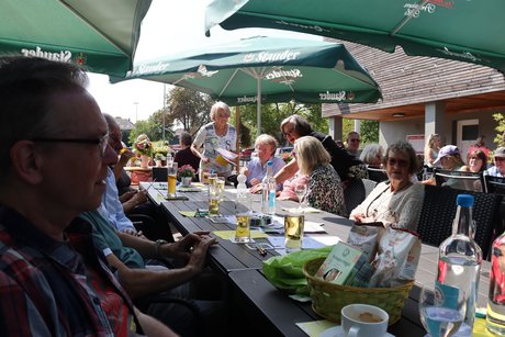 Mehrere Menschen sitzen im Biergarten an Tischen,