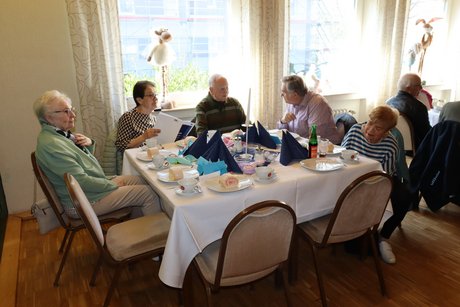 Mehrere Personen sitzen an einem gedeckten Tisch und unterhalten sich.