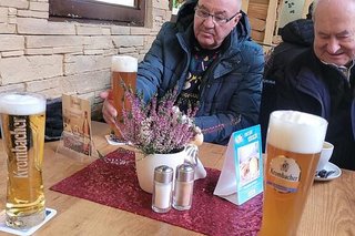 Zwei Männer sitzen bei großen Gläsern Bier an einem Café-Tisch.