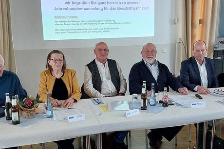 Fünf Männer und eine Frau sitzen nebeneinander an einem langen Tisch. Auf dem Tisch stehen kleine Bier- und Wasserflaschen. Hinter ihnen an der Wand sieht man den Ausschnitt einer PowerPoint-Präsentation.