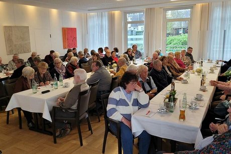 Viele Menschen sitzen an langen Tischen