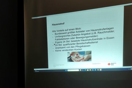 Mitgliedertreffen - Thema: Hausnotruf. Eine Präsentation auf einer Leinwand zum Thema Hausnotruf.