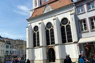 Leuchtend-weiß hebt sich die Kirche in der Altstadt von Xanten vor dem strahlendblauen Frühlingshimmel ab.