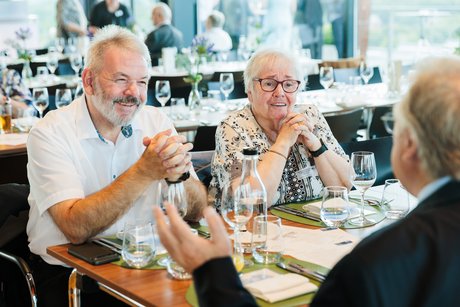 Eine Frau und ein Mann hören zu, was ihr gegenüber zu erzählen hat am Tisch.