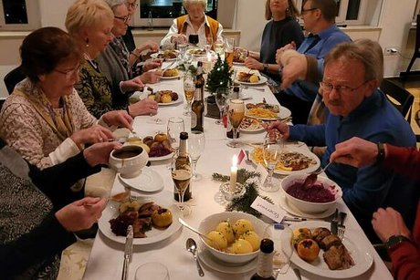 Menschen sitzen gemeinsam an einem langen Tisch beim Essen.