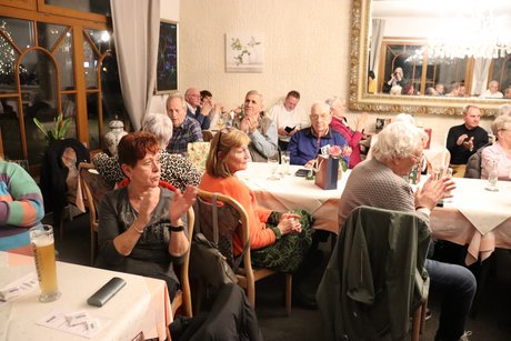 Menschen sitzen an gedeckten Tischen.