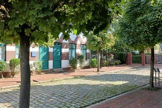 Die Kopfsteinpflaster-Straße vor dem Textilmuseum wird von mehreren Bäumen gesäumt.