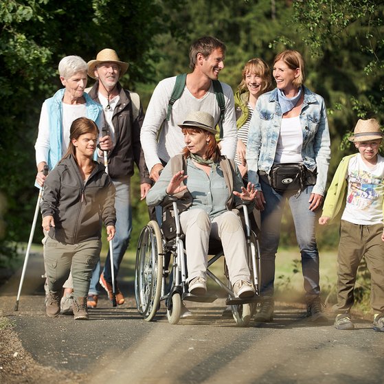 Eine Gruppe von VdK-Mitgliedern - M&auml;nner und Frauen, mit und ohne Behinderung - ist gemeinsam drau&szlig;en unterwegs wie bei einer Wanderung. Sie unterhalten sich.