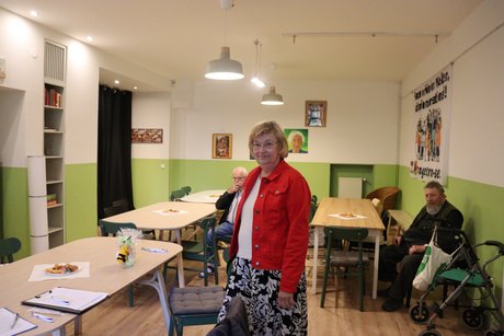 Wilma Kirschmer - Vorsitzende im Ortsverband Bredeney / Haarzopf und Vertreterin der Frauen im Kreisverband Rhein-Ruhr. Eine Frau steht im Vordergrund und dahinter sitzen an verschiedenen Tischen 2 Männer.