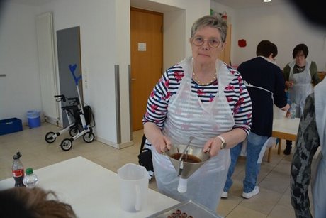 Eine Teilnehmerin befüllt Vollmilch-Kugeln mit einem Stahltrichter mit dunkler Ganache