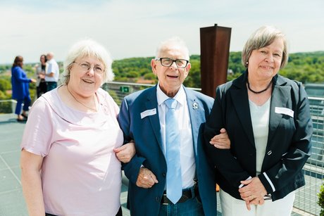 Drei Personen stehen für ein Foto zusammen.