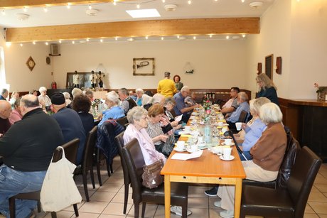 An langen Tischen sitzen mehrere Menschen.