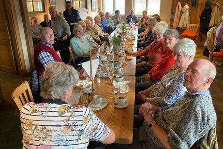 Männer und Frauen sitzen gemeinsam an einer langen Tafel.