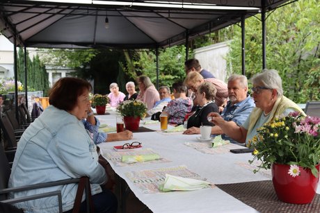 Grillnachmittag vom VdK Ortsverband Altendorf gemeinsam mit dem Ortsverband Borbeck. Teilnehmer sitzen an einem langen Tisch unter einem Pavillon im Außenbereich.