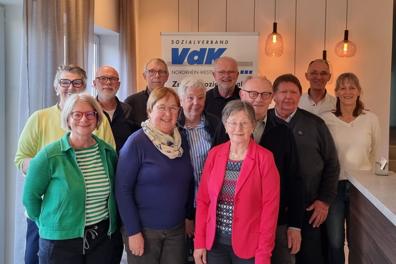 Das Foto zeigt eine Gruppe von zw&ouml;lf Personen, die freundlich lachen.