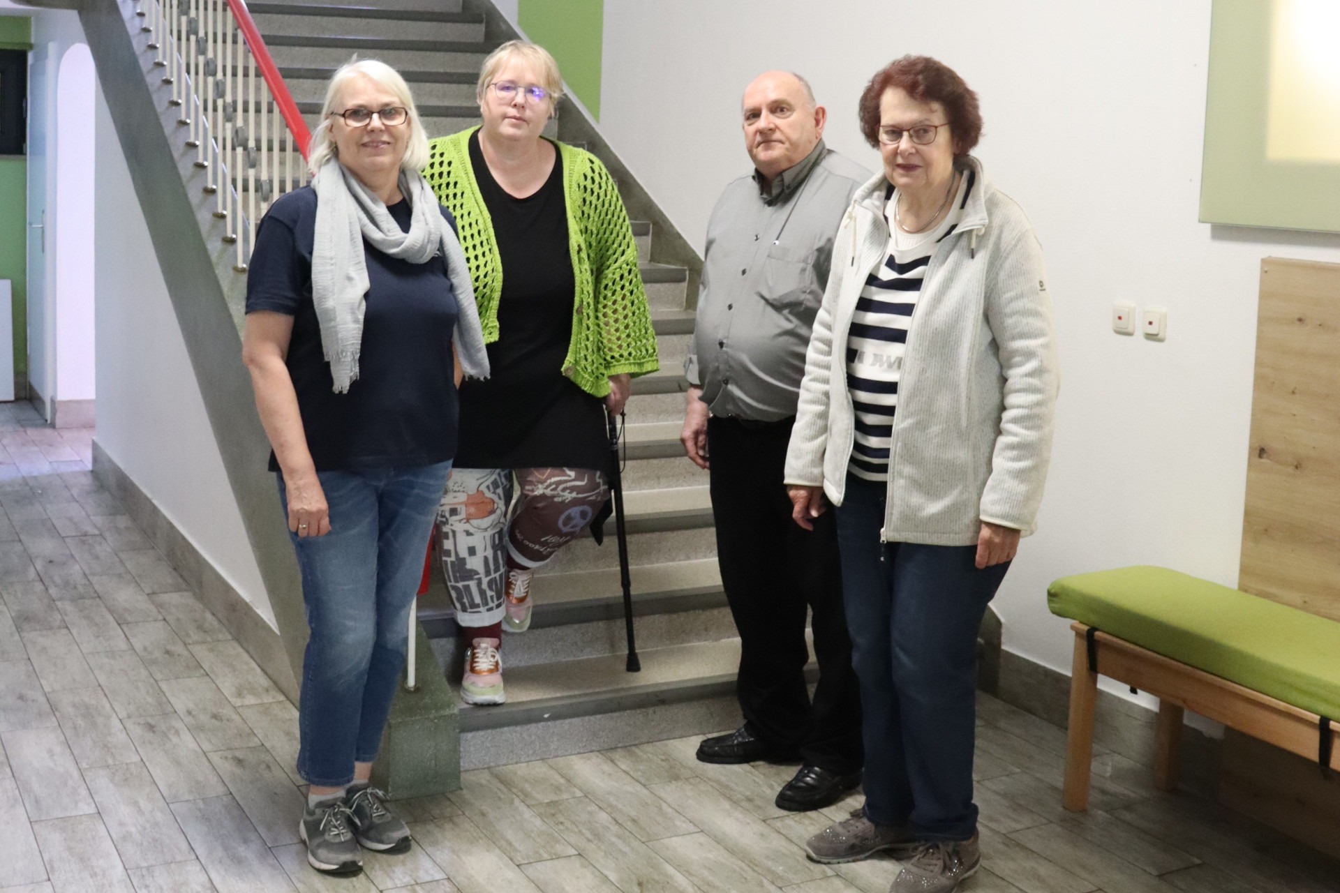 Drei Frauen und ein Mann stehen an einer Treppe für ein Gruppenbild zusammen.