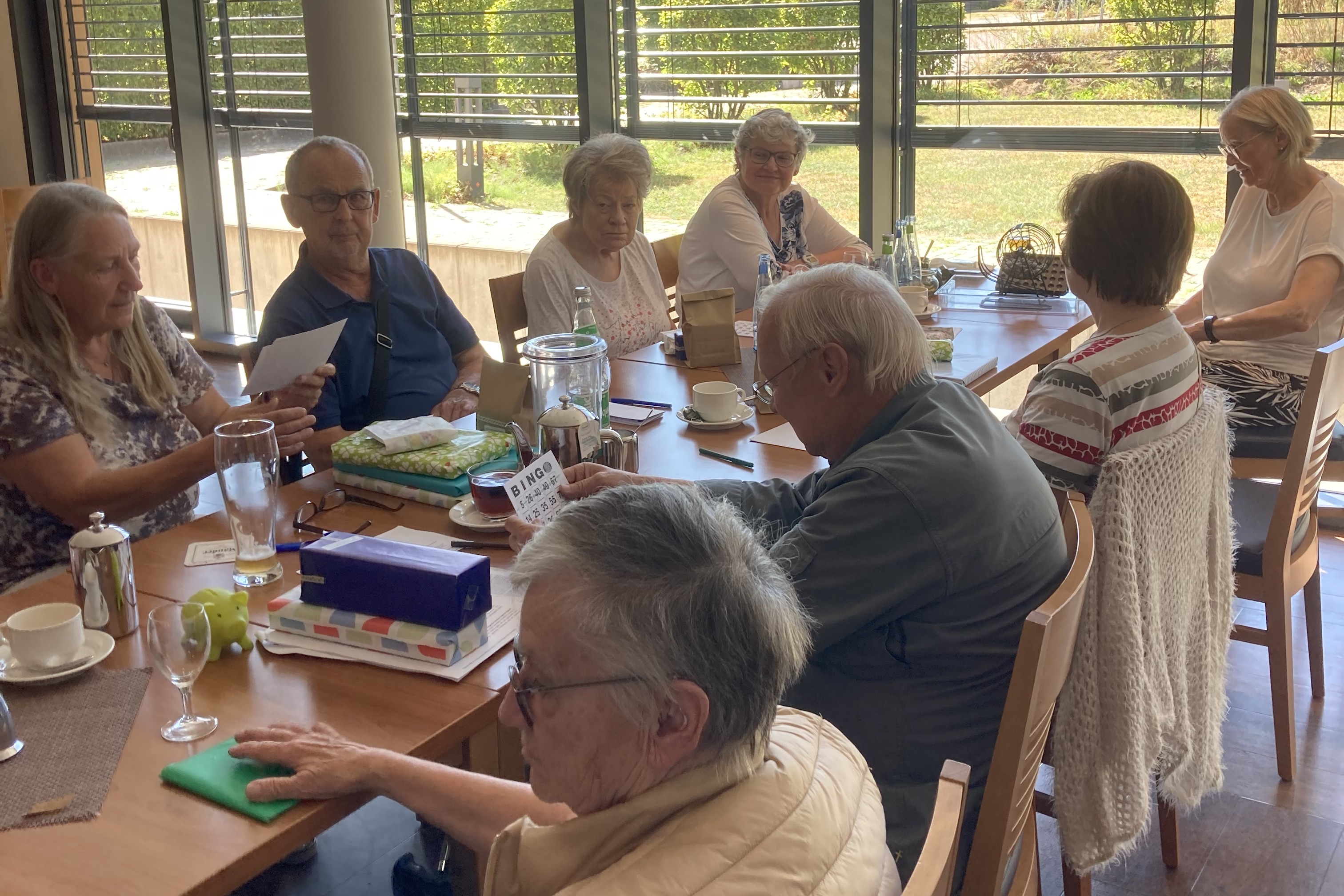 Menschen sitzen an einem langen Tisch und unterhalten sich miteinander.