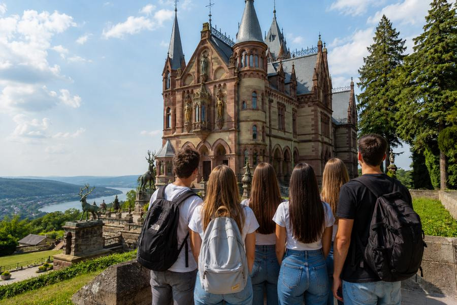 Das Foto zeigt eine Touristengruppe vor dem Schloss Drachenburg mit Blick auf die Rheinschleife