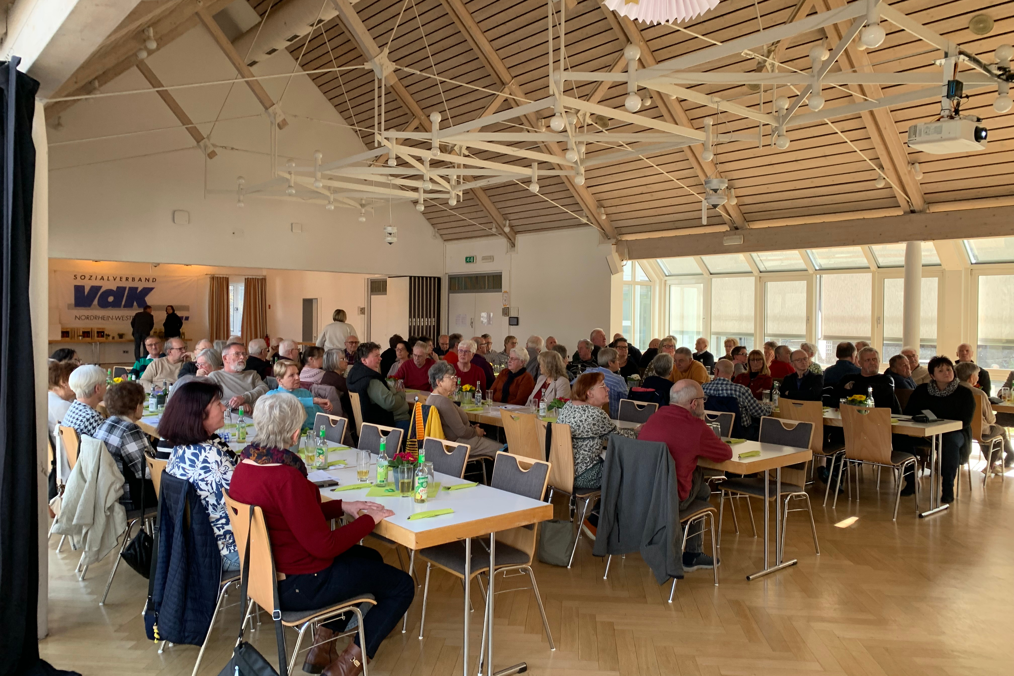 Saal mit Menschen an Tischen sitzend