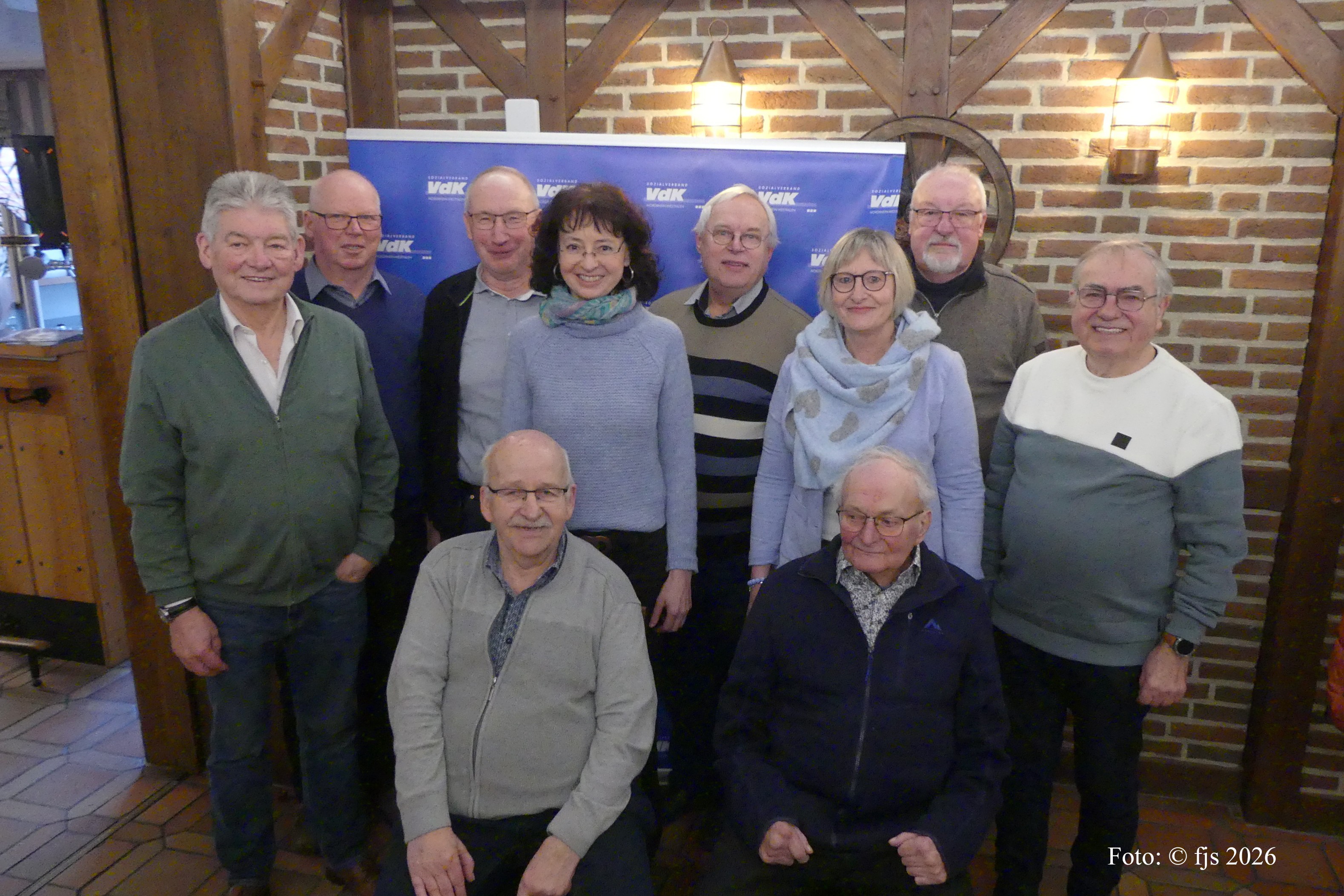 10 Personen stehen als Gruppe vor einer VdK-Leinwand