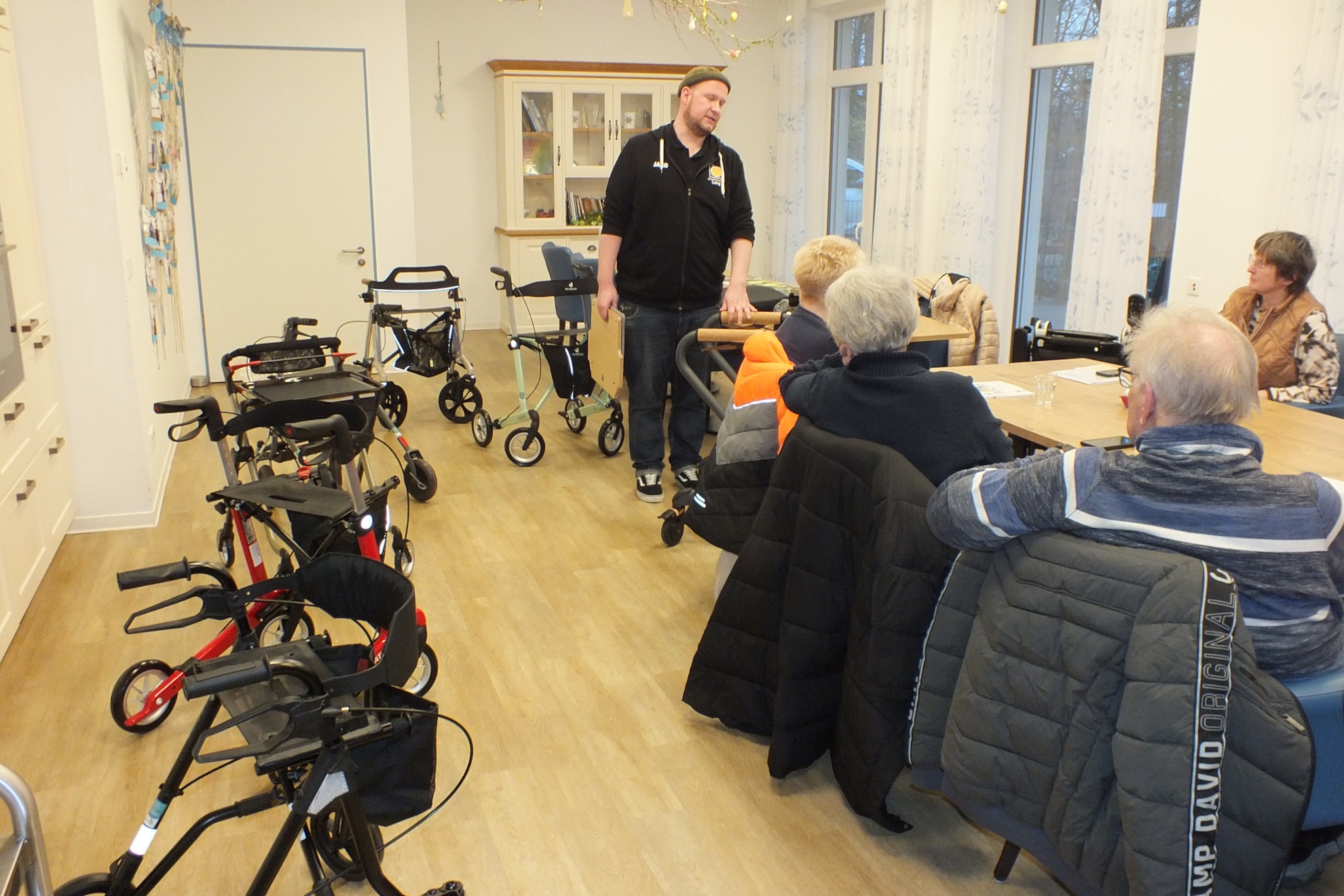 Ein Mann steht vor einer Gruppe und daneben stehen unterschiedliche Rollator Modelle.