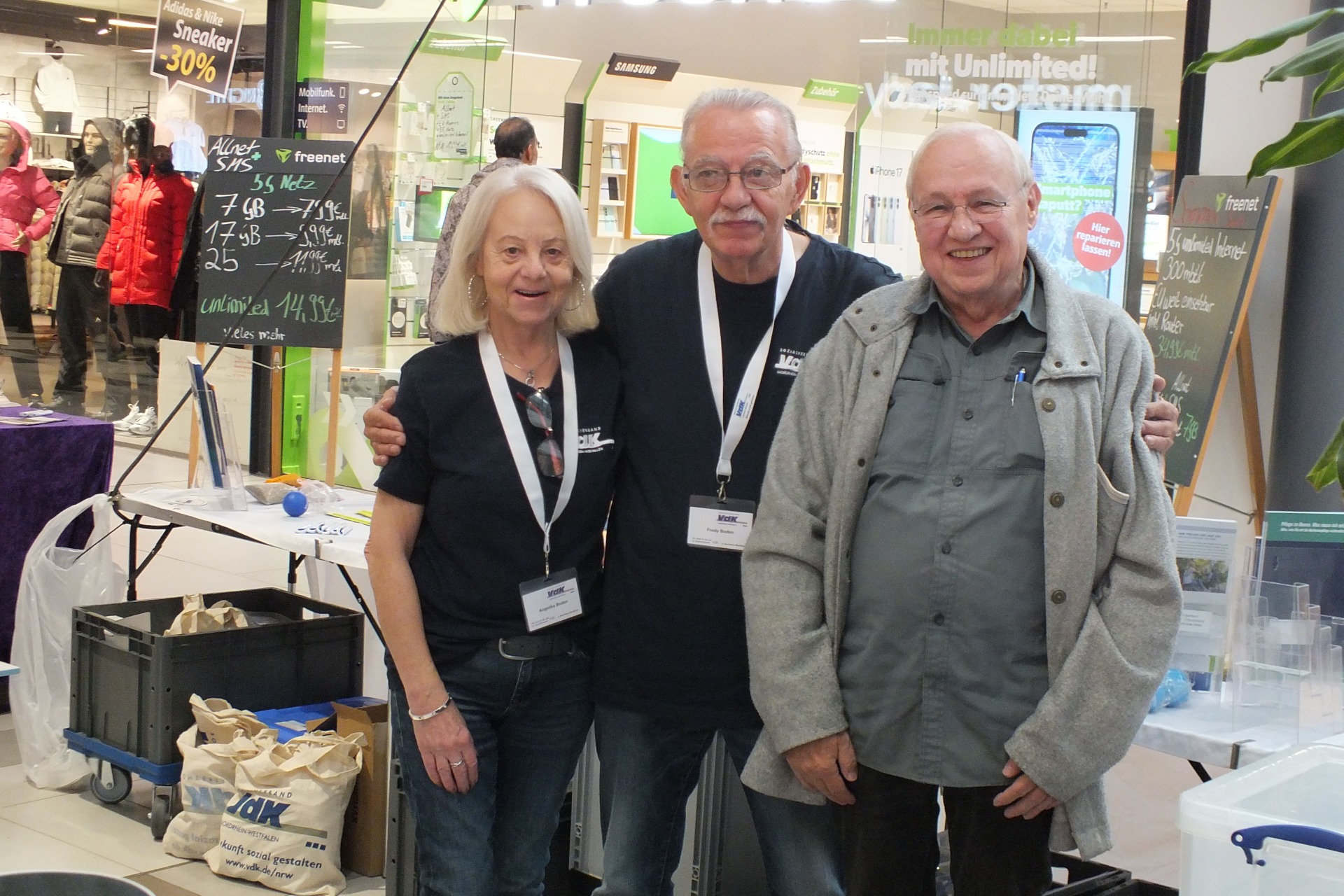 Drei Personen stehen vor einem VdK Info-Stand.