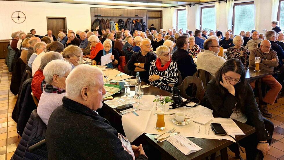 Viele Menschen sitzen an Tischen in einem Saal