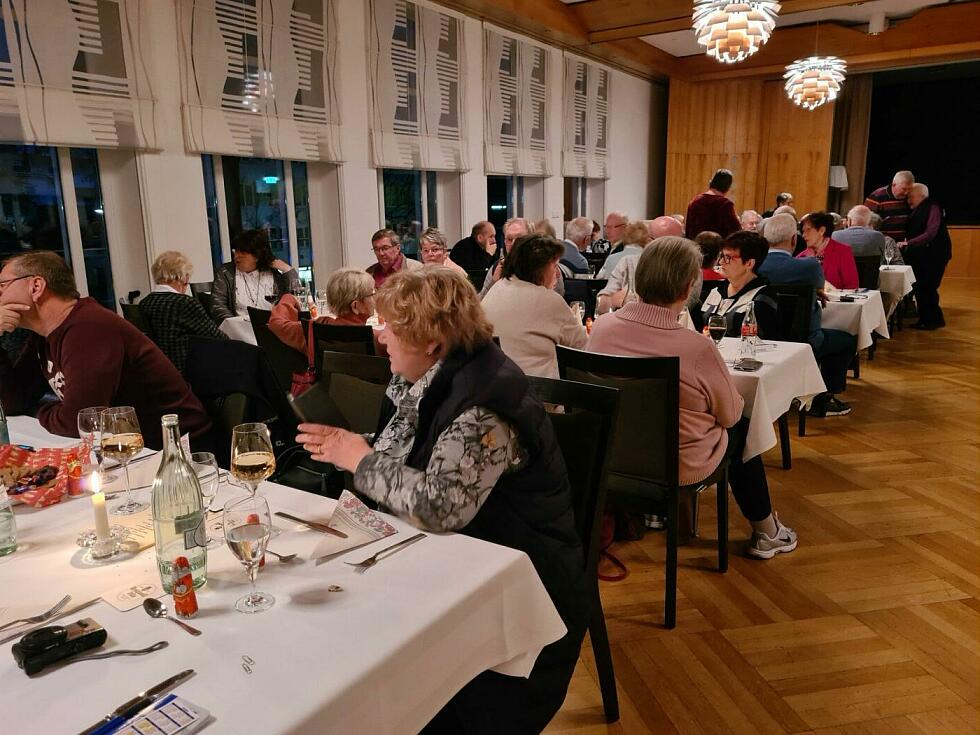 Viele Menschen sitzen an weihnachtlich gedeckten Tischen