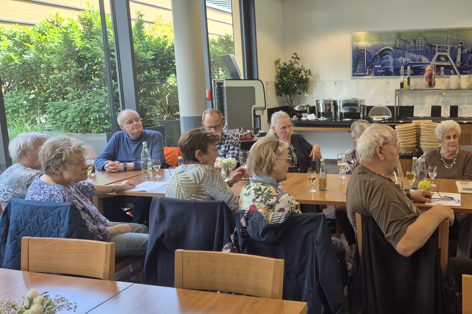Mitgliedertreffen - Thema: Contigo-Ruhr Senioren Beratung und Teilhabe. Mitglieder sitzen an Tischen und hören dem Vortrag zu.