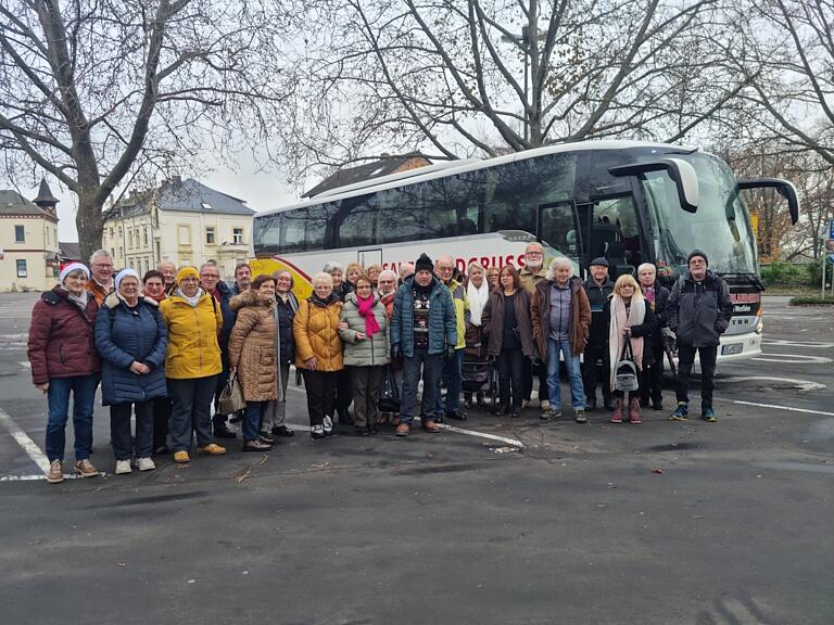 Das Bild zeigt die Teilnehmer am Tagesausflug nach Rüdesheim als Gruppe aufgestellt vor dem Reisebus auf einem baumbestandenen Parkplatz.