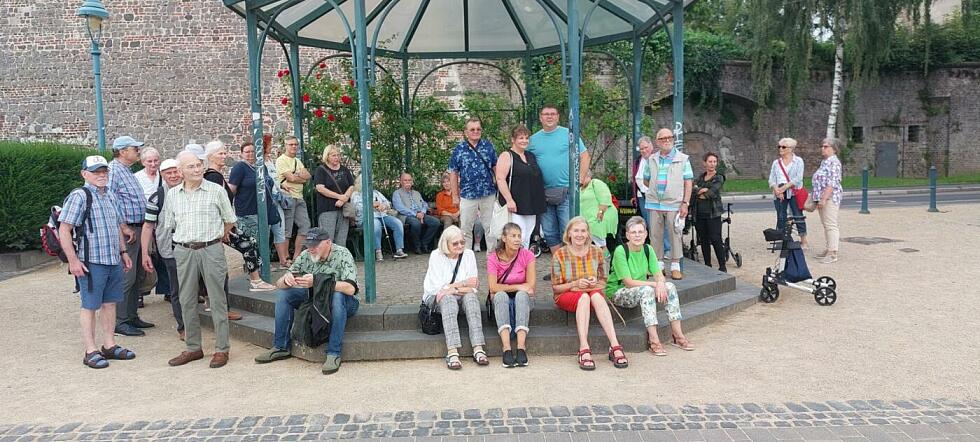 Gruppenfoto der Reisegruppe unter und neben einem mit Rosen bewachsenen Glaspavillons.