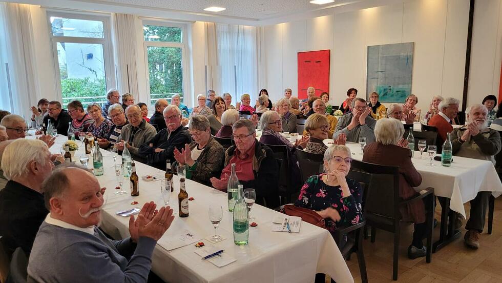 Viele Menschen sitzen an Tischen in einem Saal