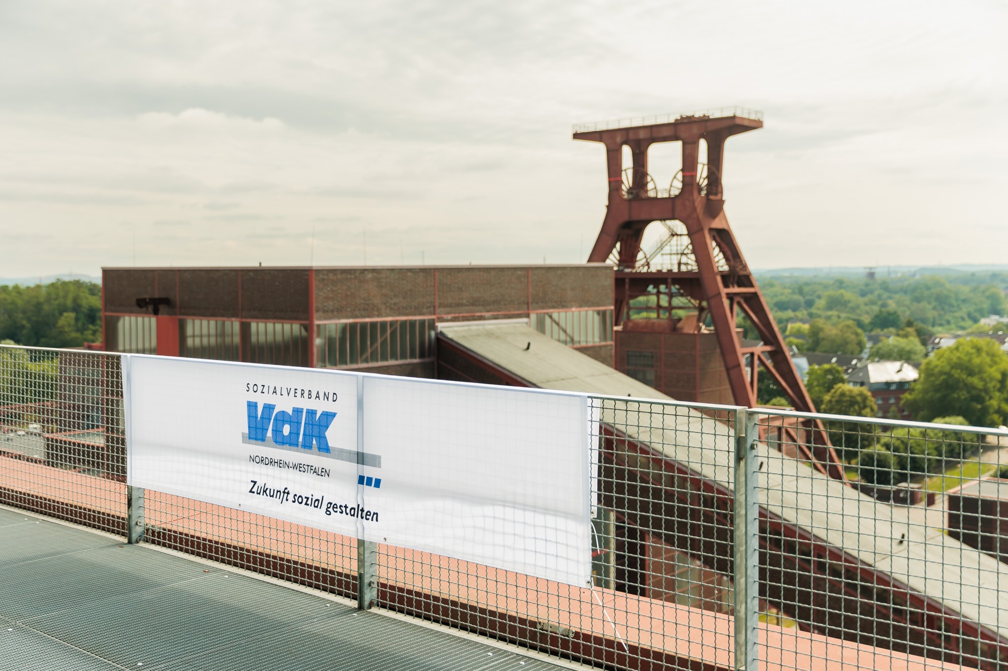 Ein VdK-Banner hängt an einem Geländer vor dem Ausblick auf einen Förderturm