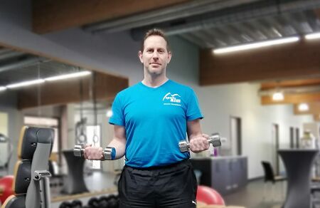 Ein Mann mit Hanteln steht in einem Fitness-Raum