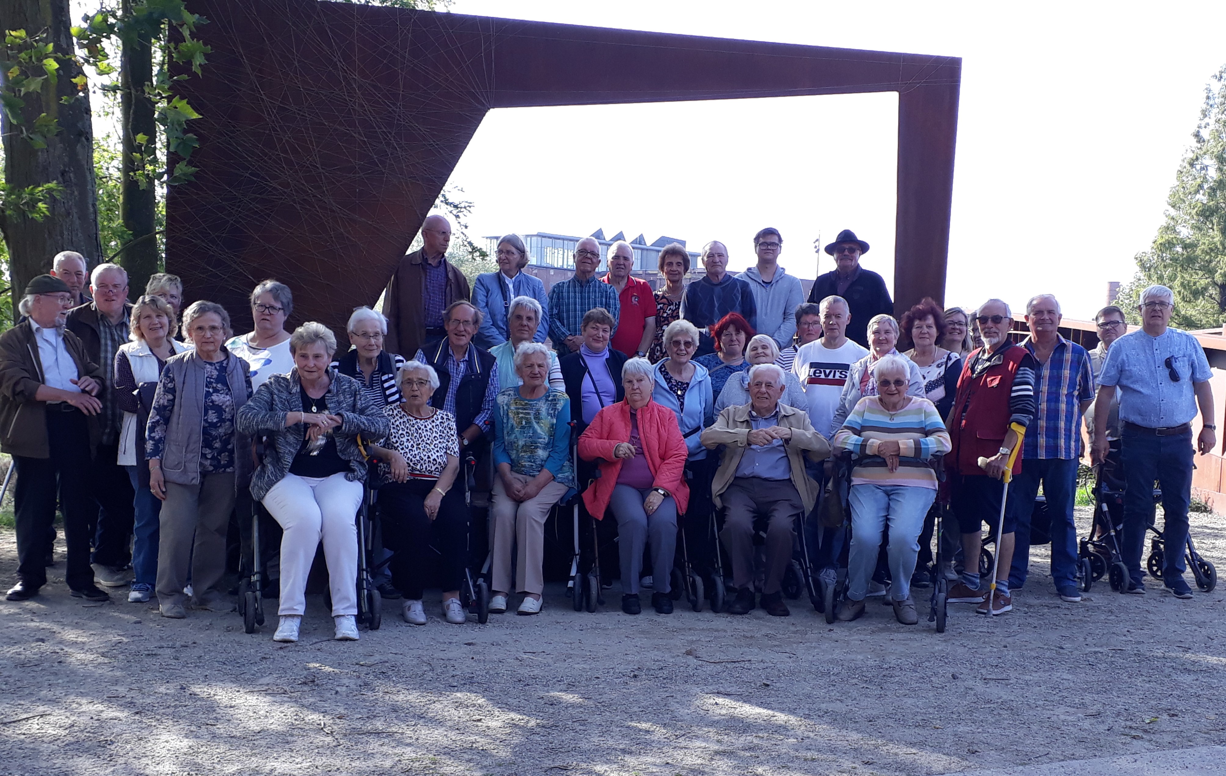 Das Bild zeigt die Besuchergruppe vor einem Denkmal aus Stahl