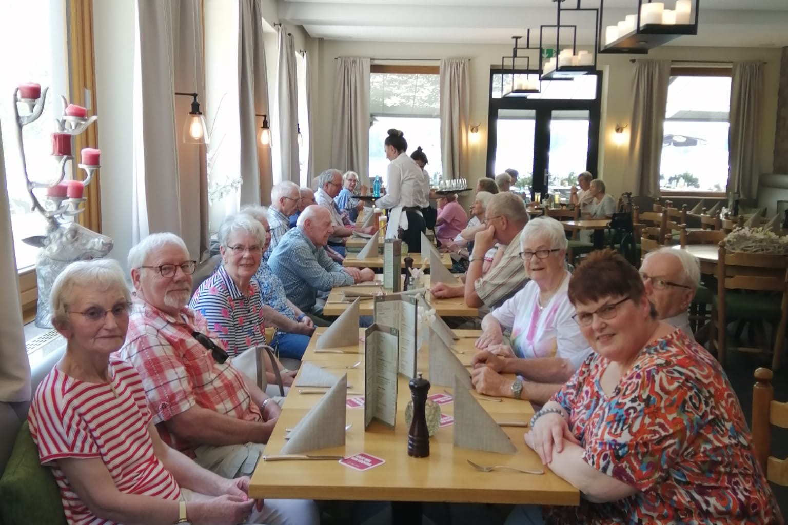 Das Bild zeigt eine Gruppe der Reiseteilnehmenden, die an dem gedeckten Mittagstisch sitzen.