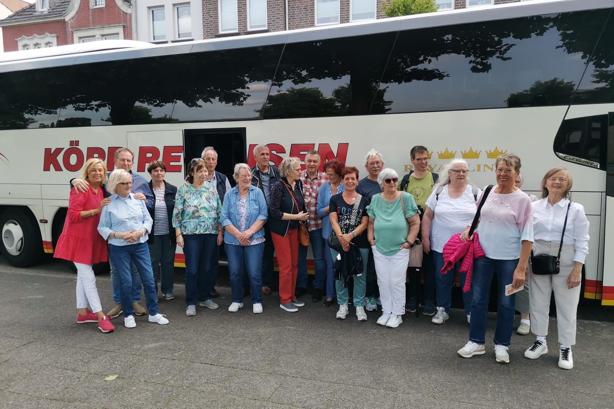 Tagesfahrt zum Spargelhof Schippers mit Weiterfahrt nach Kevelaer. Viele Menschen stehen vor einem Reisebus zum Gruppenfoto zusammen.