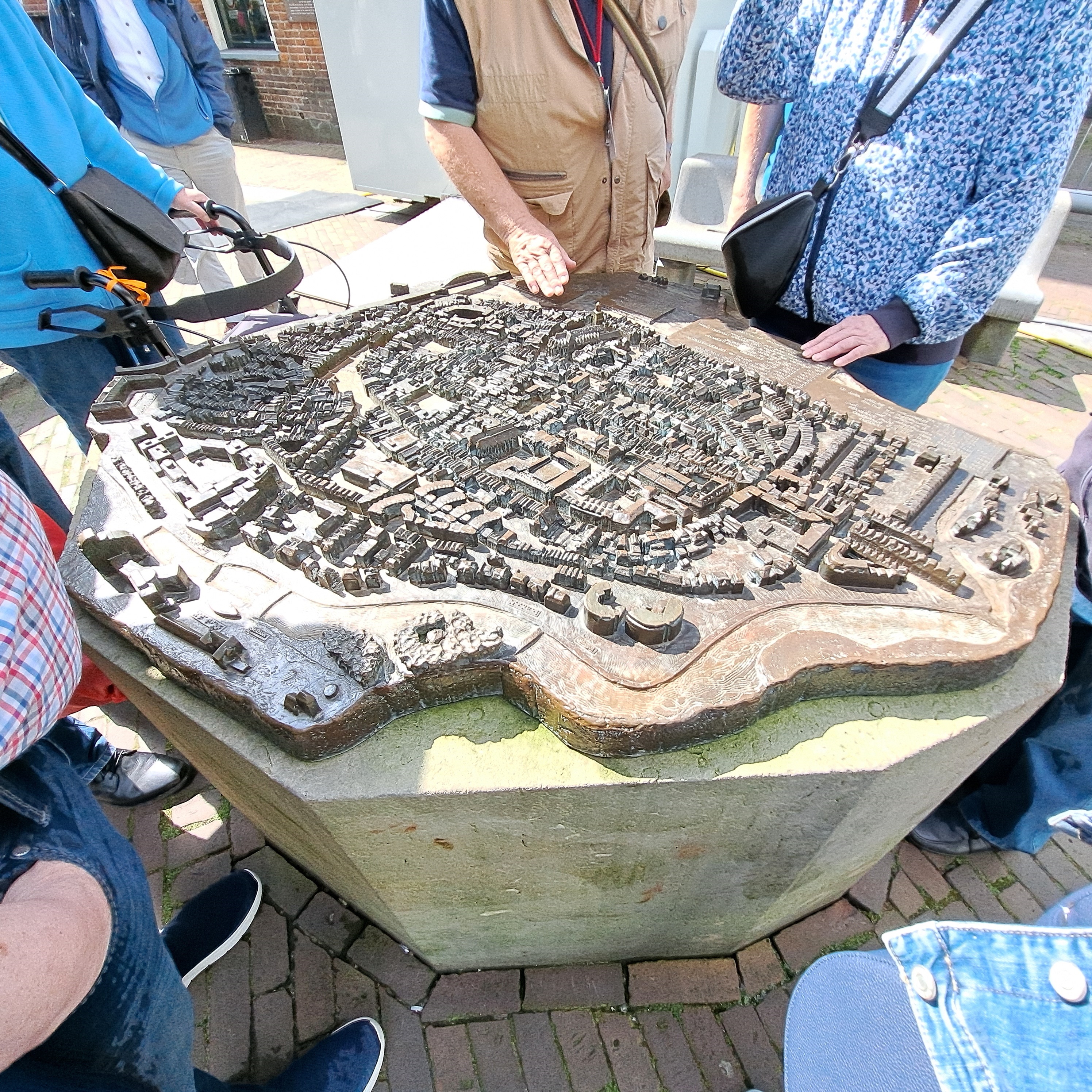 Menschen stehen um ein Bronze-Relief für sehbehinderte und blinde Menschen herum.