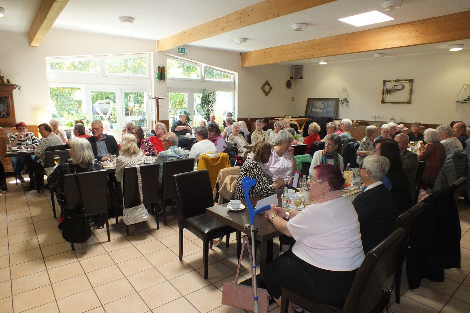 Viele Menschen sitzen an mehreren langen Tischen.