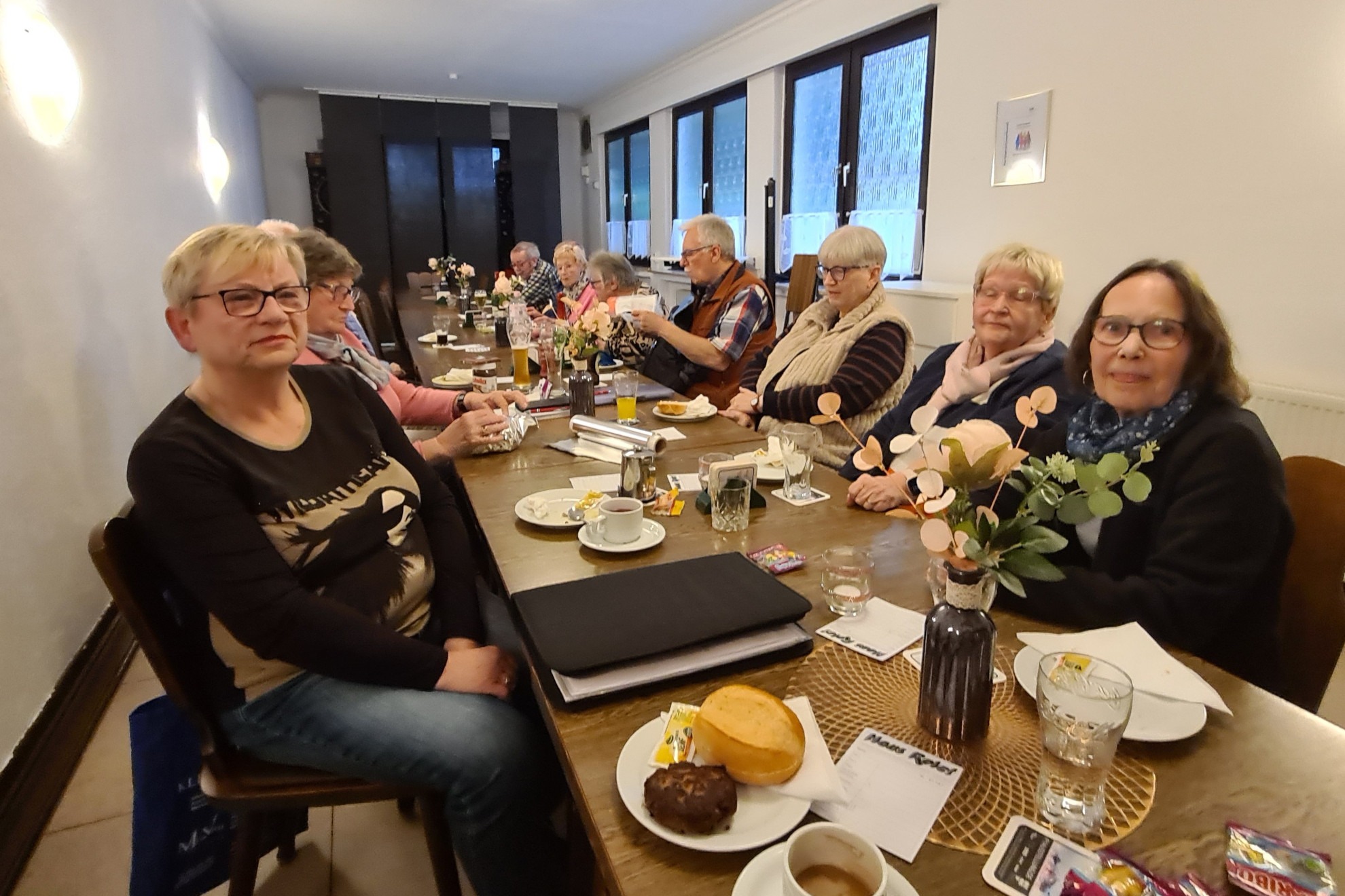 Mehrere Personen sitzen an einem langen Tisch und unterhalten sich miteinander.