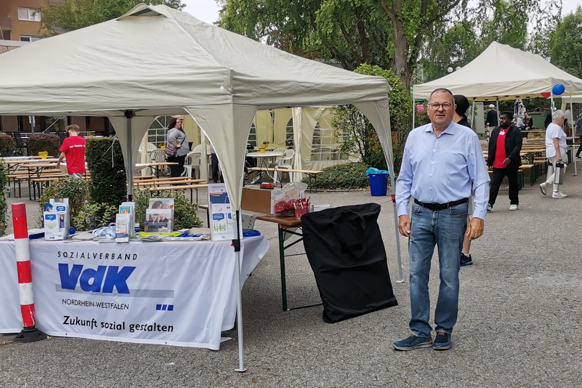 ein Mann steht neben einem VdK Info-Stand.