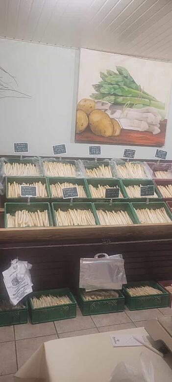 Unterschiedlicher Spargel ist in grünen Kisten entlang einer Wand aufgestapelt.