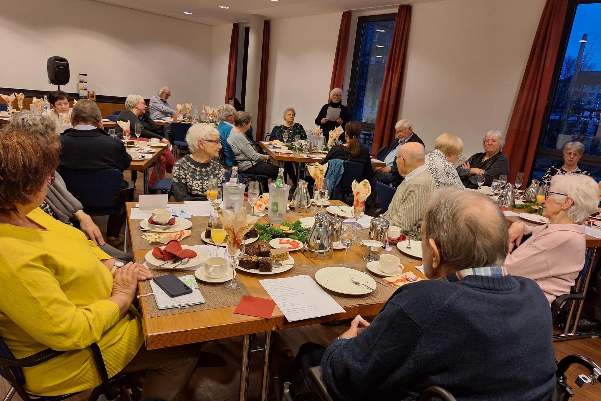 Mehrere Menschen sitzen an gedeckten Tischen.