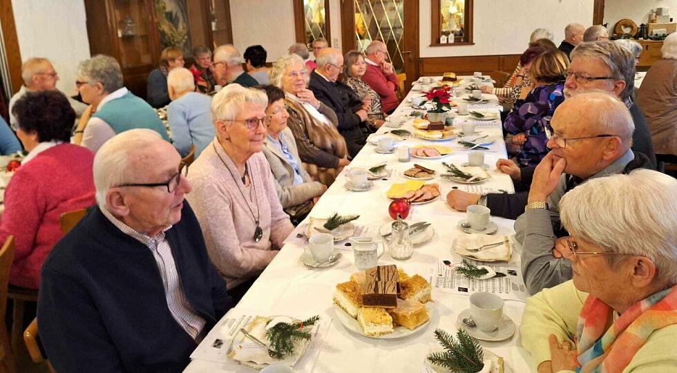 Viele Menschen sitzen an festlich eingedeckten Tischen in einem Saal