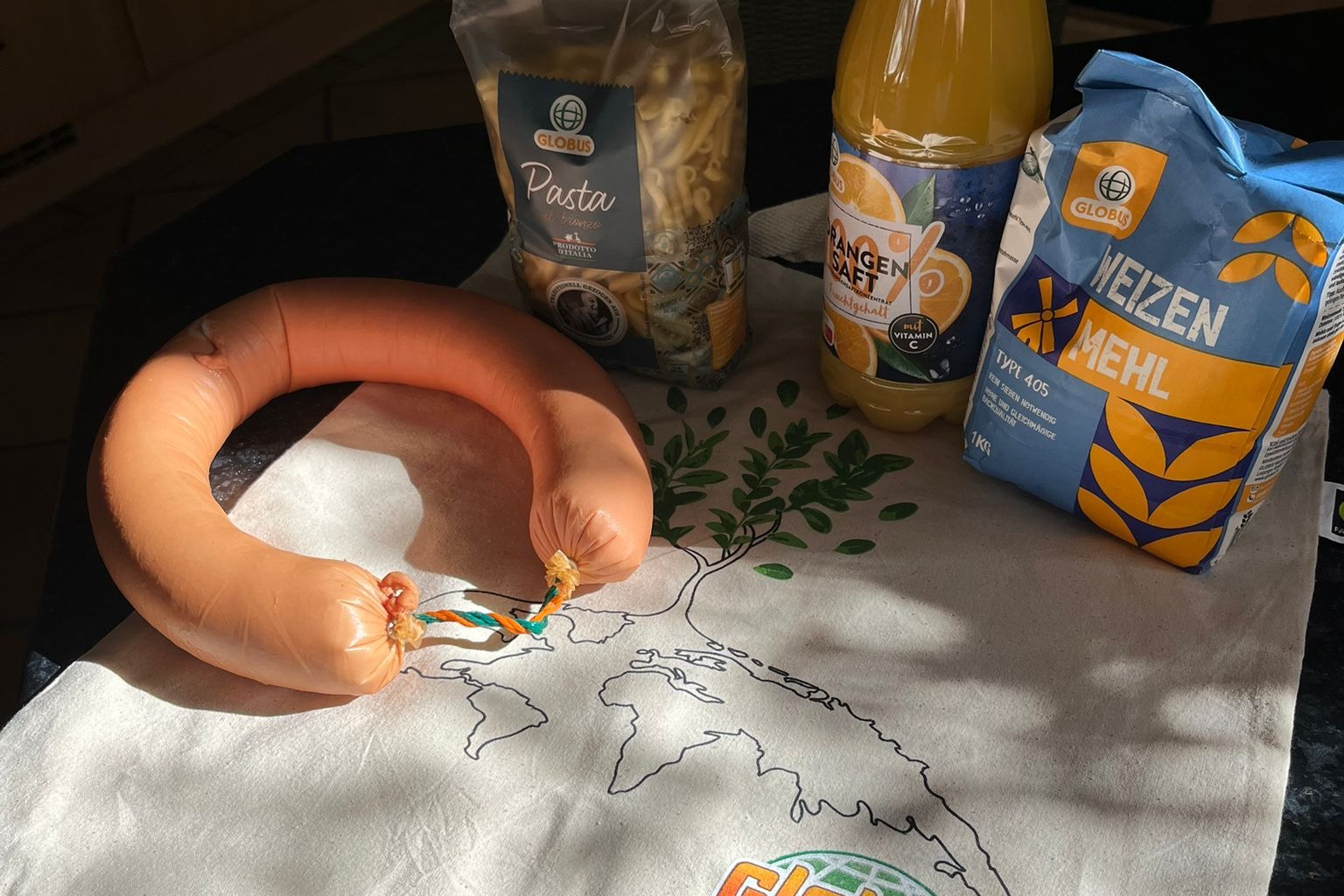 Auf dem Bild ist das Geschenk mit O-Saft , Weißenmehl , Nudeln und ein Ring Fleischwurst