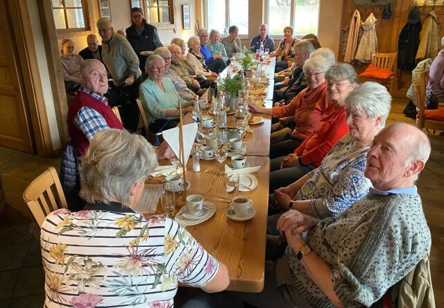 Männer und Frauen sitzen gemeinsam an einer langen Tafel.