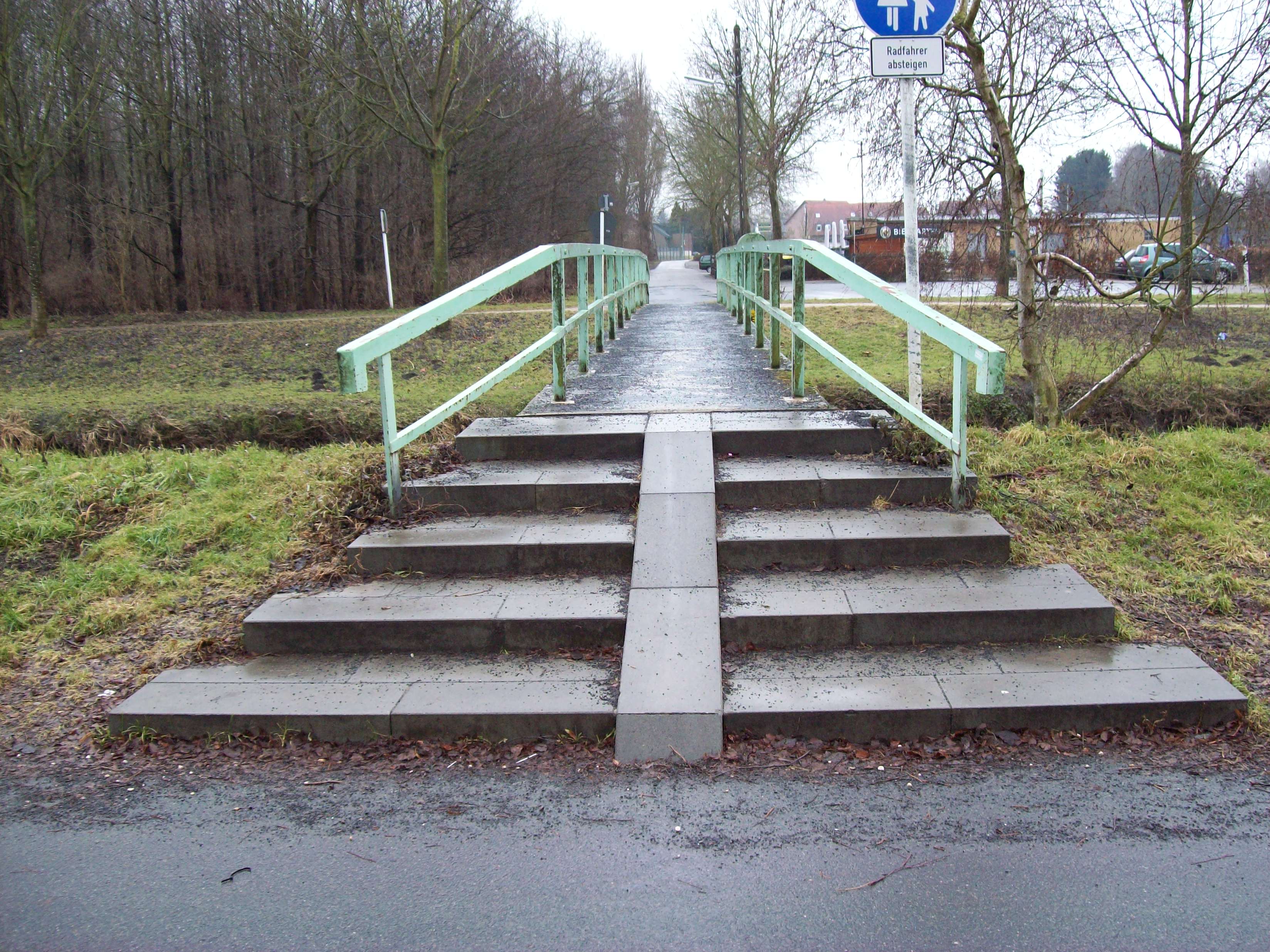 Eine Fußgängerbrücke deren Treppenstufen durch eine schmale Schrägfläche geteilt werden.